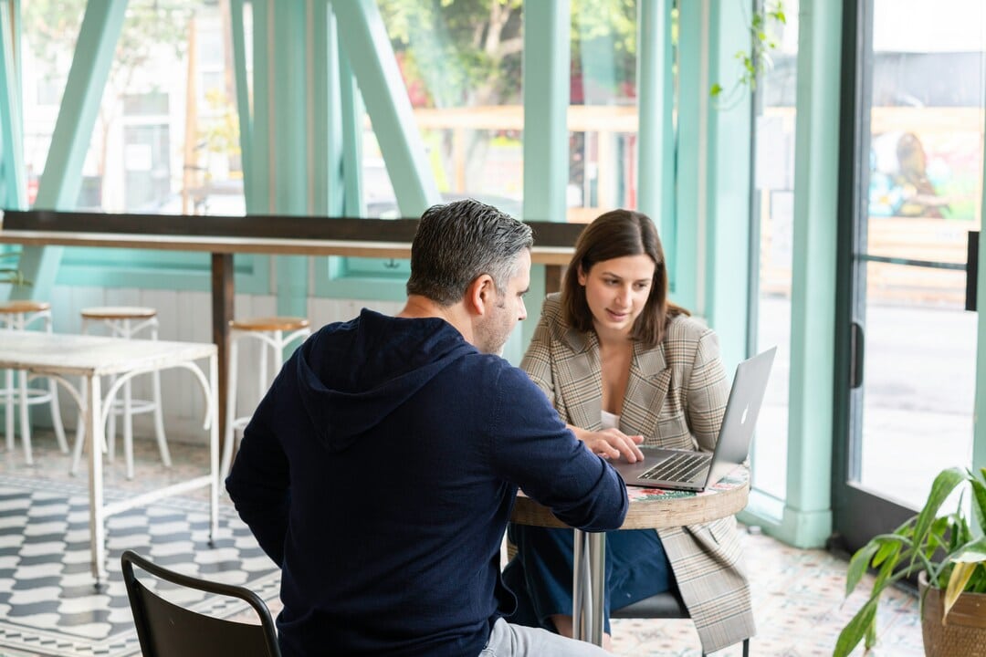 Two people sitting at a table on a computer
